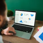 A man doing PPC audit of the campaign using laptop and charts